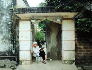 Old lady sitting in front of her ancient house in Duong Lam ANcient Village